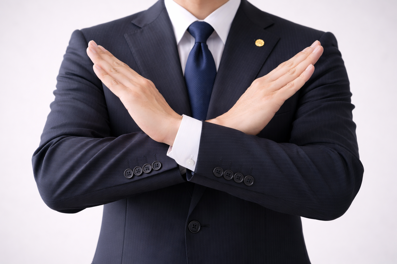 弁護士が胸元で腕でバツサインをしている様子